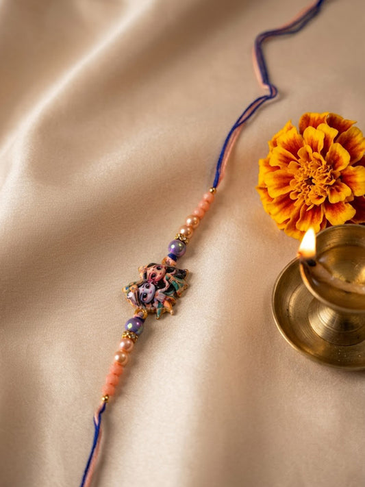 NVR Radha Krishna Multicolor Artificial Beads Thread Rakhi With Roli Chawal Chandan Mishri